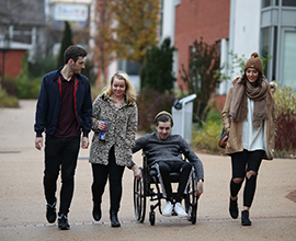 Four students walking through campus together